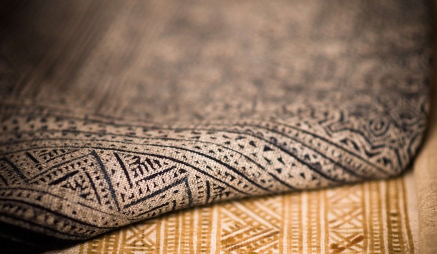 Close-up of two textured fabrics with intricate geometric patterns, one in dark tones and the other in lighter shades.